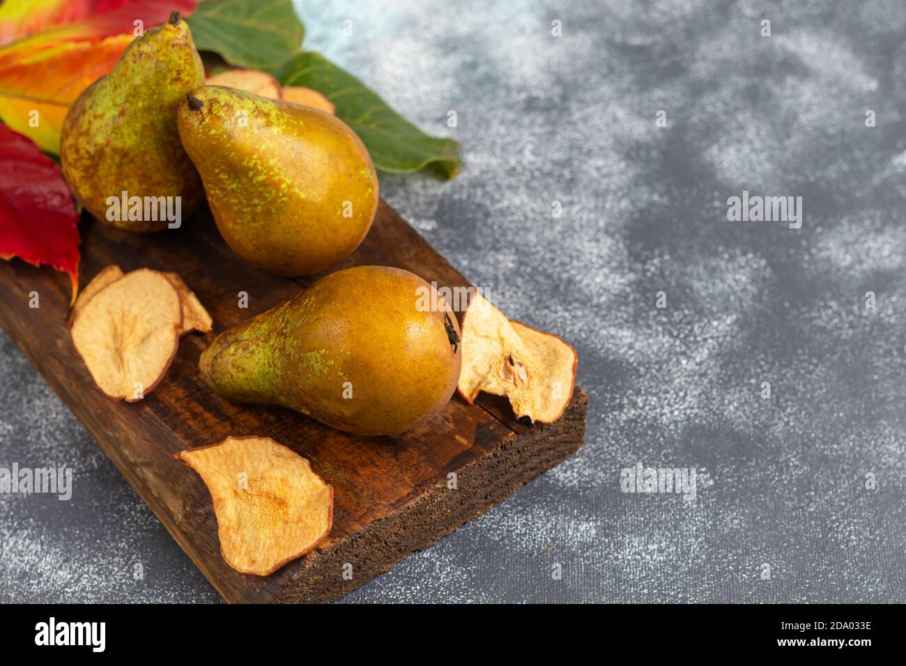 Pere su uno sfondo chiaro. Concetto autunnale. Nelle vicinanze si trovano patatine e noci di pera secca. Spazio di copia. Foto Stock