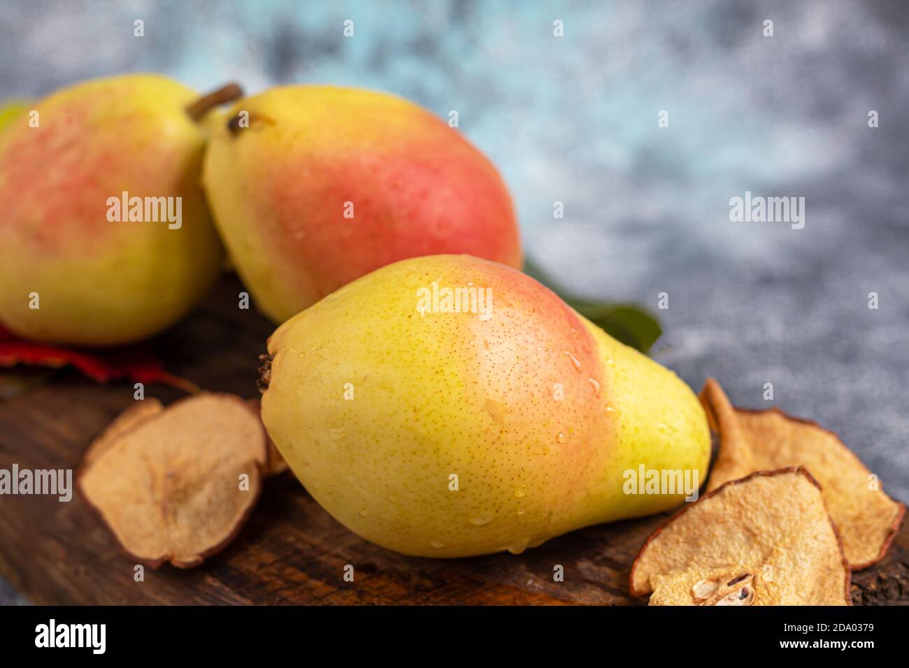 Pere su uno sfondo chiaro. Concetto autunnale. Nelle vicinanze si trovano patatine e noci di pera secca. Spazio di copia. Foto Stock