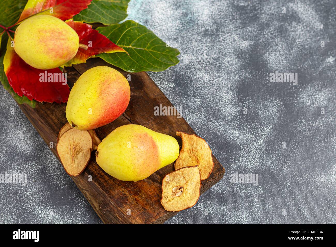 Pere su uno sfondo chiaro. Concetto autunnale. Nelle vicinanze si trovano patatine e noci di pera secca. Spazio di copia. Foto Stock