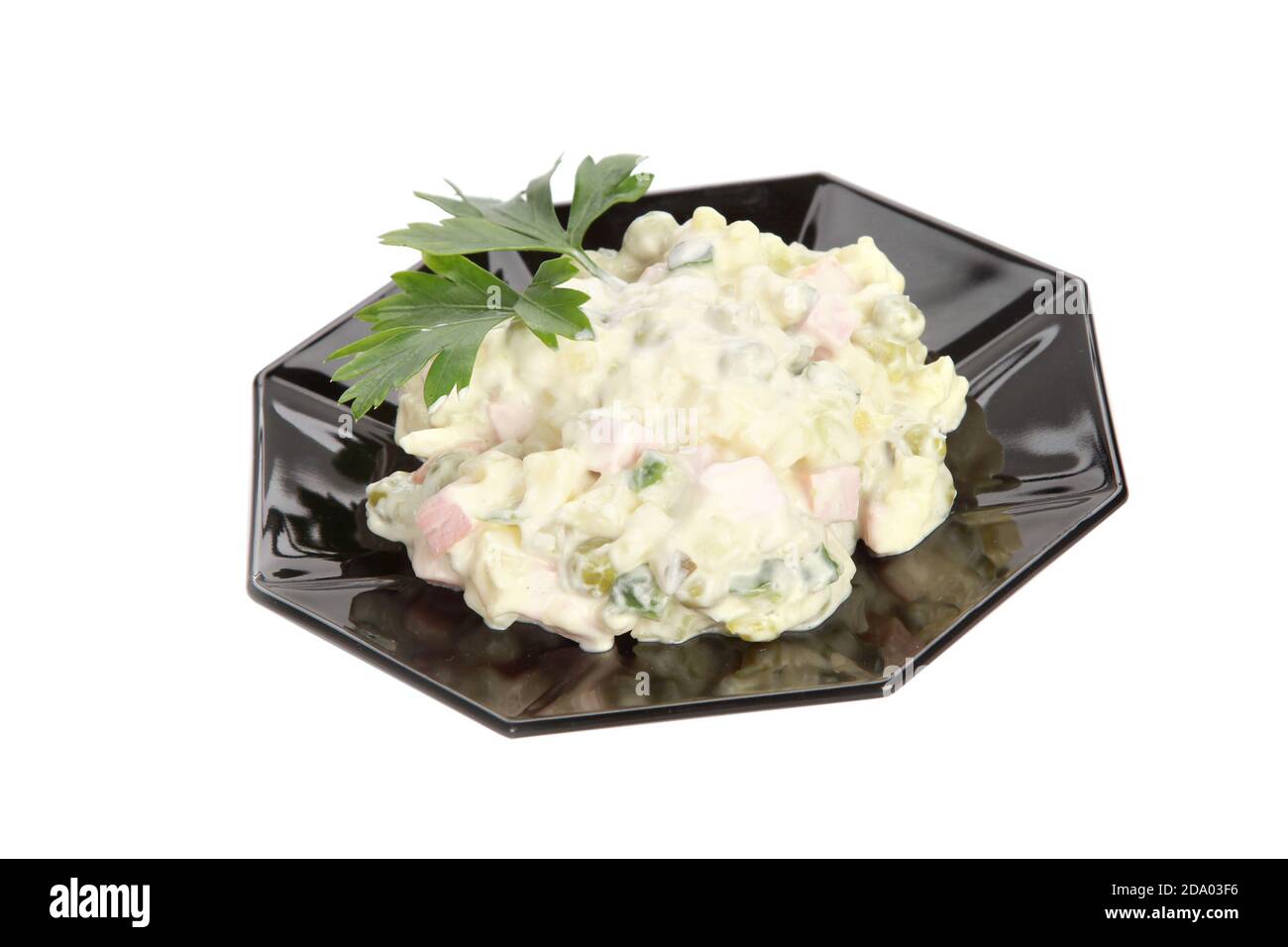 Primo piano di una tradizionale insalata olivier al buio piastra isolata su sfondo bianco Foto Stock