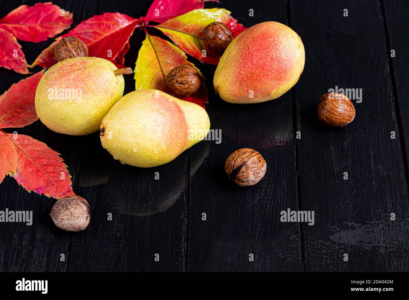 Pere su uno sfondo chiaro. Concetto autunnale. Nelle vicinanze si trovano patatine e noci di pera secca. Spazio di copia. Foto Stock