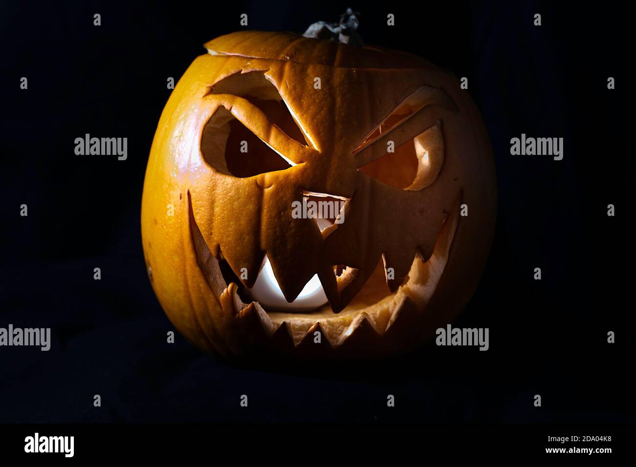 Jack o'Lantern ha illuminato la zucca con il sorriso malvagio isolato su un Sfondo nero - tradizione di Halloween Foto Stock