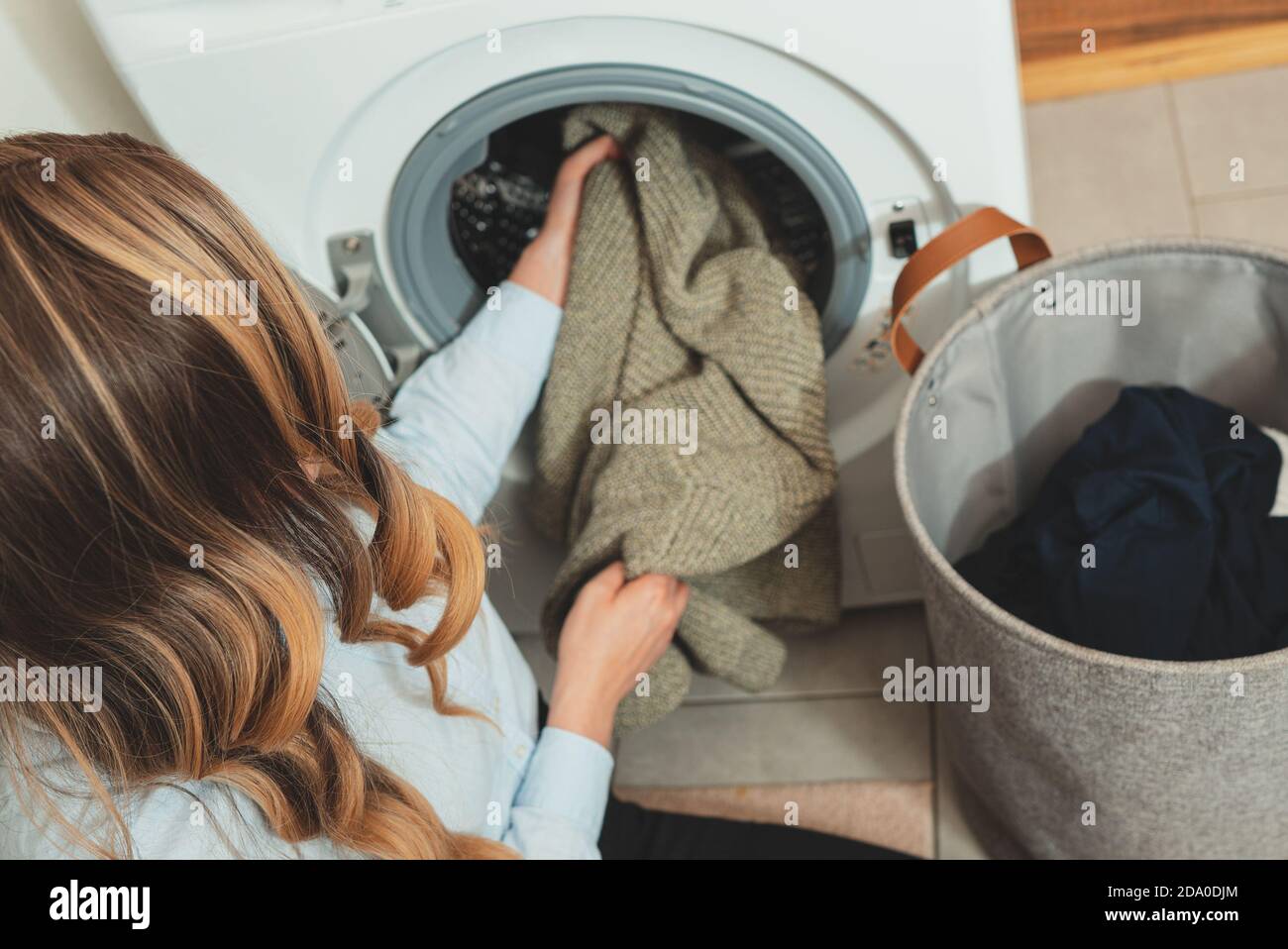 Donna che carica i vestiti nella lavatrice. Foto Stock