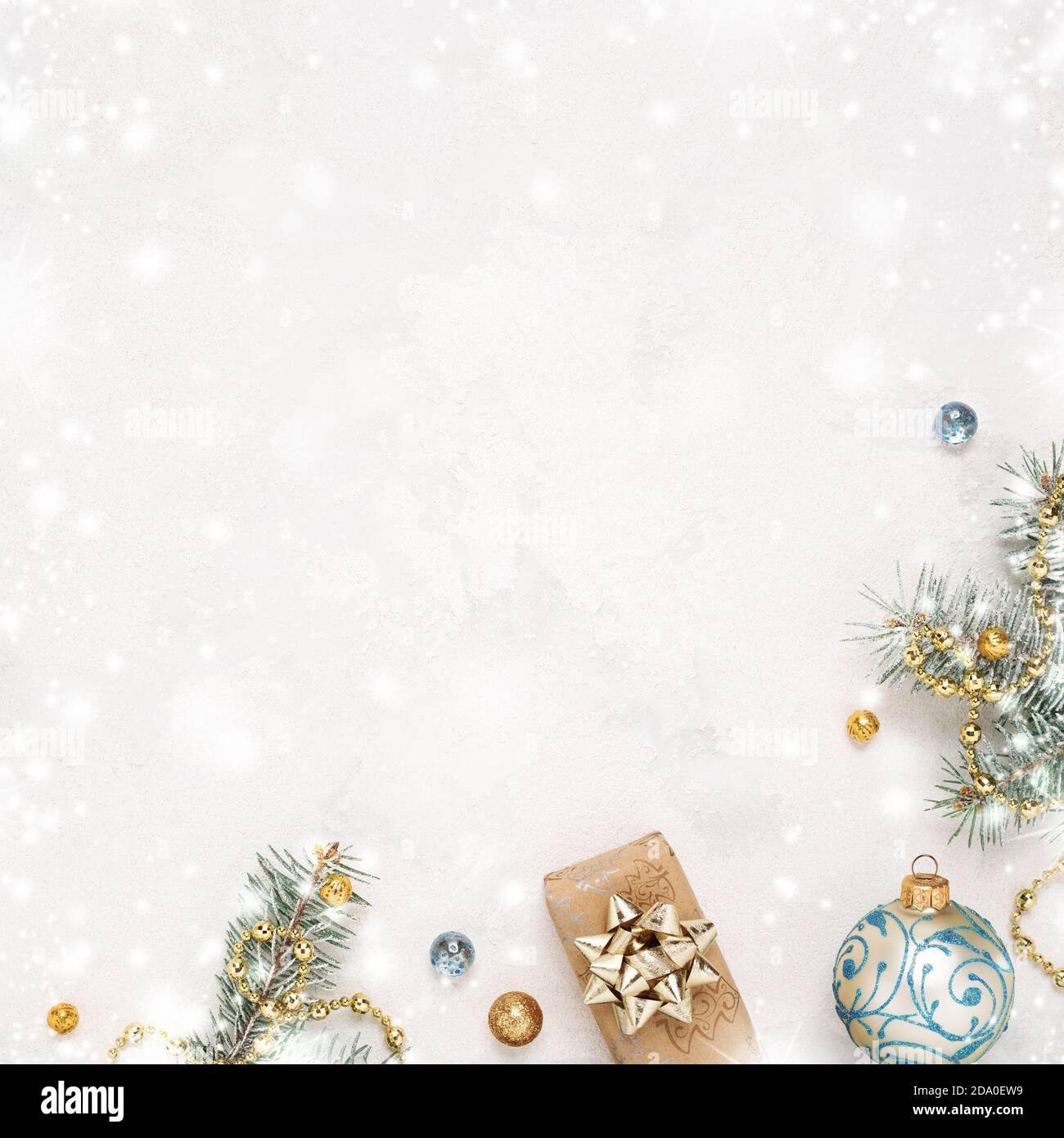 Natale fondo bianco neve con regalo, ramoscelli di abete, decorazioni blu oro. Spazio di copia. Cornice di Natale. Foto Stock