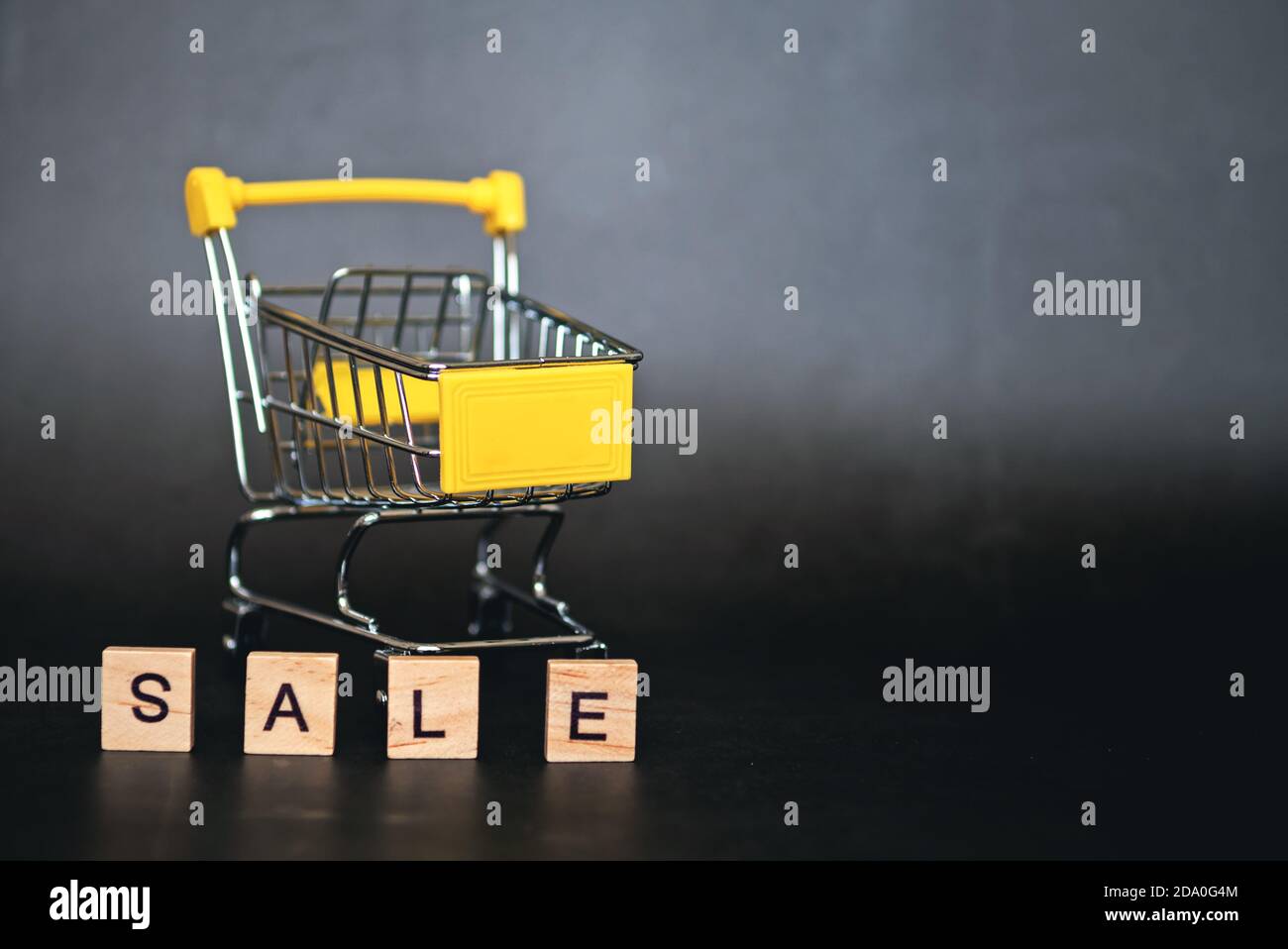 Stagione di vendite in negozi online. Carrello e parole di vendita su sfondo blu scuro. Idea creativa per una vendita, una promozione, o un concetto per il cyber Lunedi o Bla Foto Stock