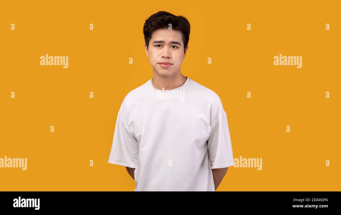 Ritratto di attraente ragazzo asiatico in posa in studio arancione Foto Stock