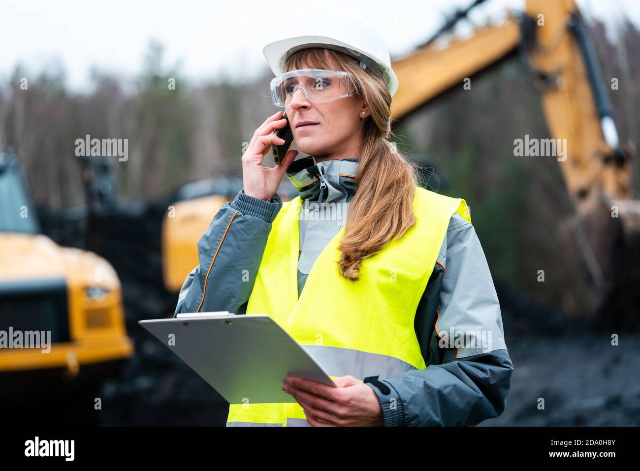 Lavoratore donna in le miniere a cielo aperto usando il telefono Foto Stock
