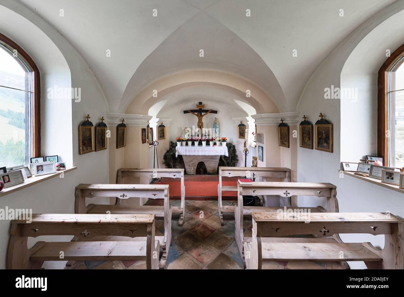 La luminosa luce risplende attraverso le finestre all'interno della cappella, le panchine e l'altare di Ackernalm alp, Tirolo, Austria Foto Stock