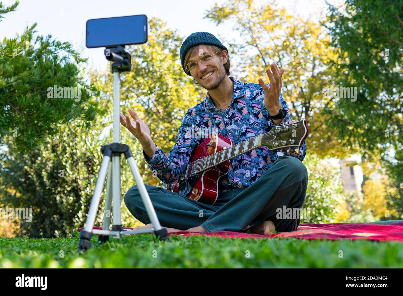 Piano terra di bell'uomo seduto con chitarra elettrica in parcheggia e  registra video su smartphone per blog sui social network media Foto stock -  Alamy