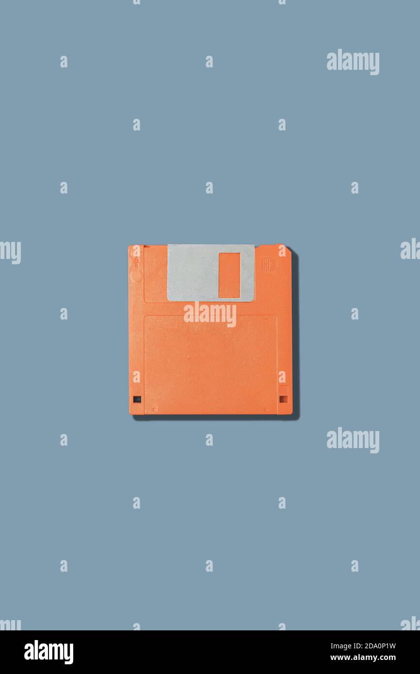 Vista dall'alto del vecchio floppy disk magnetico arancione per computer posizionato su sfondo grigio Foto Stock