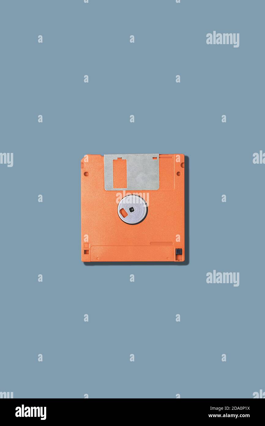 Vista dall'alto del vecchio floppy disk magnetico arancione per computer posizionato su sfondo grigio Foto Stock