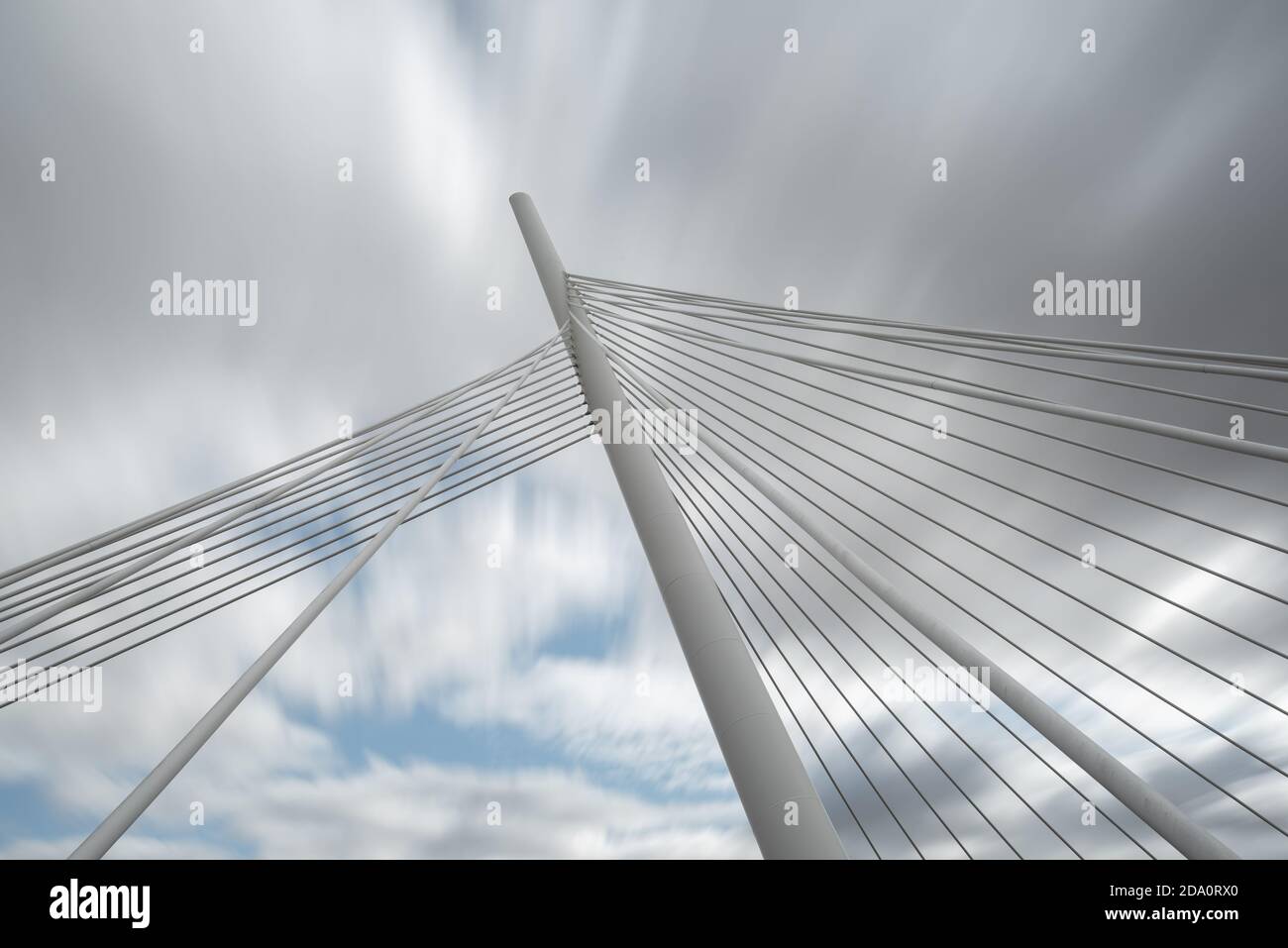 Dal basso di bianco ponte sospeso contemporaneo con colonna alta collegamento di più cavi insieme contro il cielo blu Foto Stock