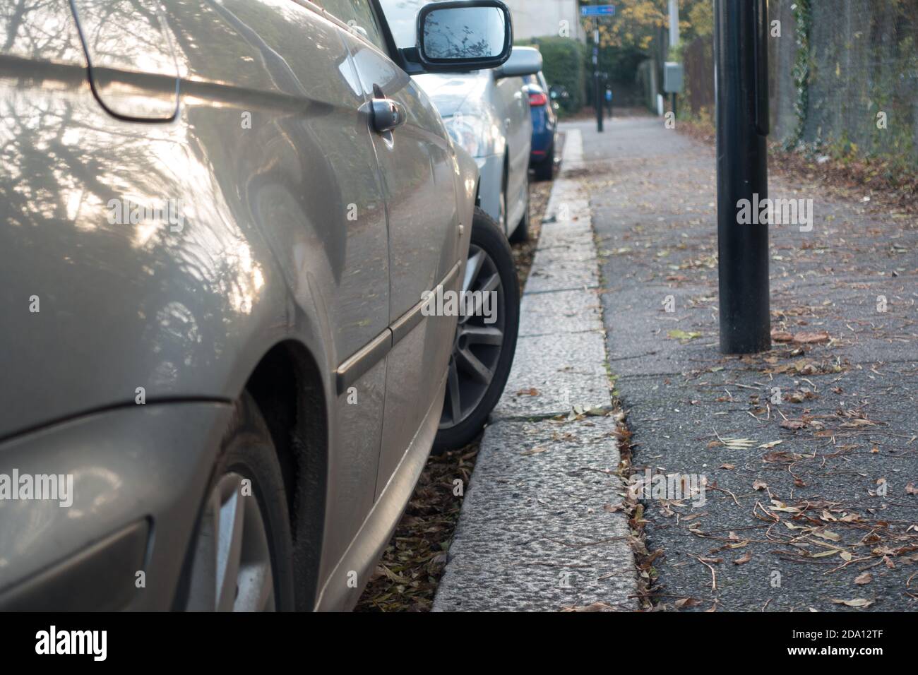 Auto parcheggiata con ruota incastrata sul marciapiede Foto Stock