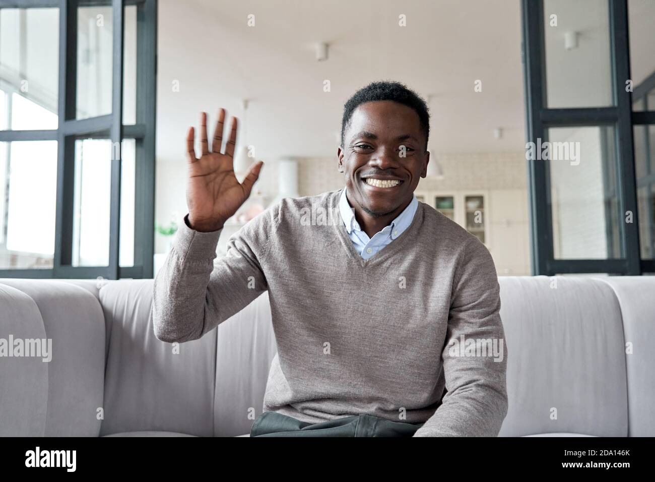 Felice giovane africano che sventolava la mano guardando la videochiamata in conferenza. Foto Stock