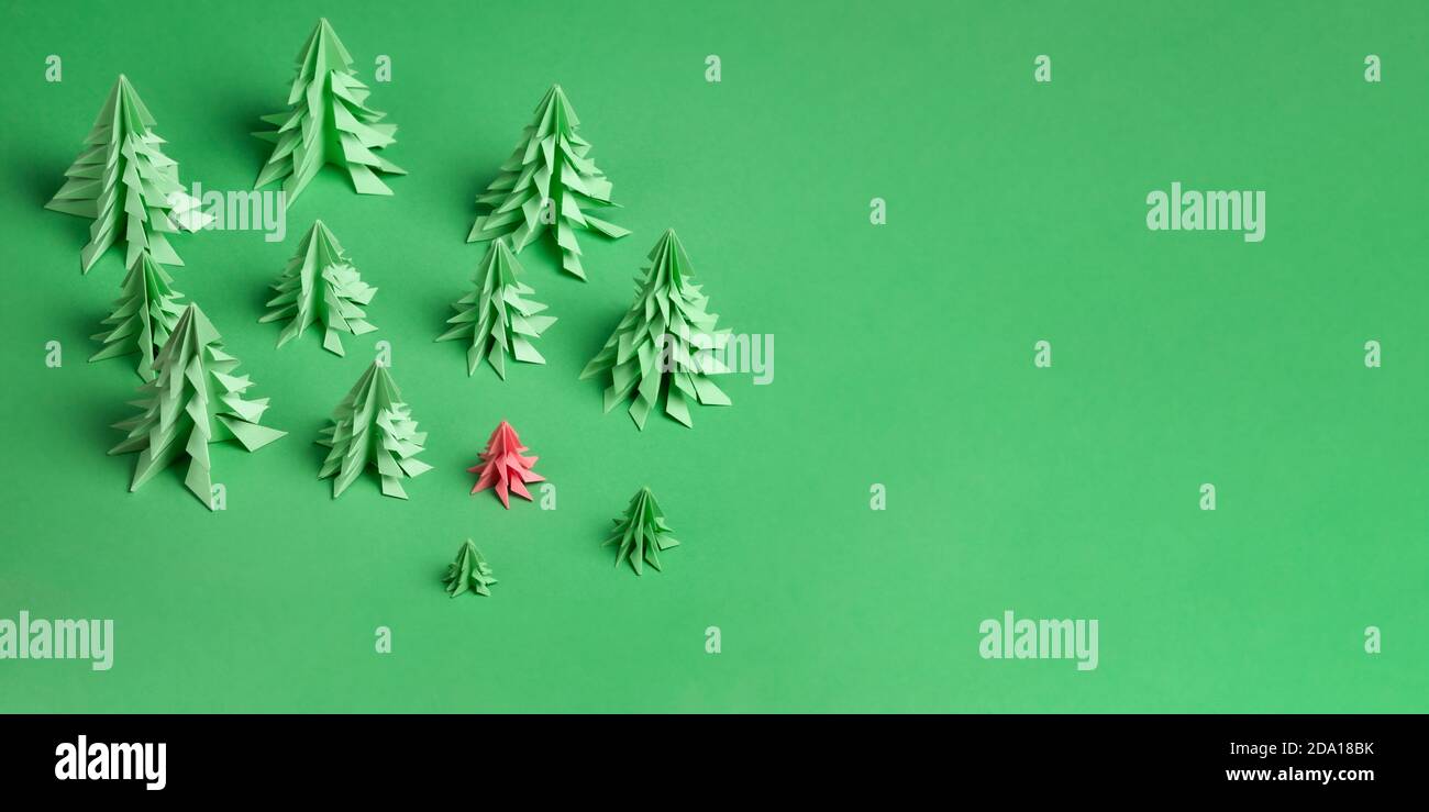 Diversi alberi di Natale di carta realizzati utilizzando la tecnica origami su sfondo di carta verde. Alcuni alberi verdi e rosa. Non come altro concetto Foto Stock