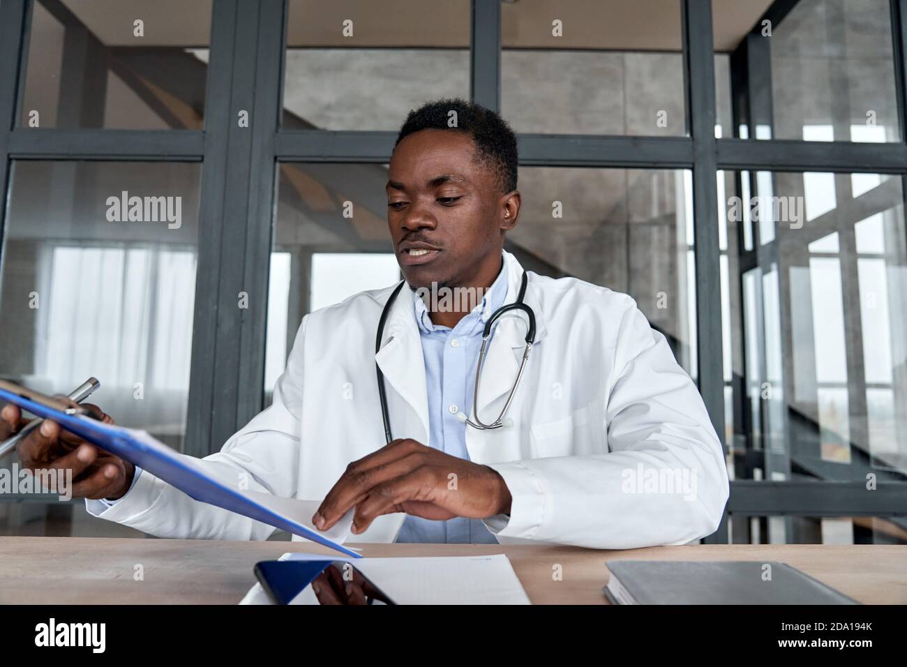 Medico di sesso maschile nero che controlla i risultati dei test del paziente tramite consiglio virtuale di telemedicina. Foto Stock
