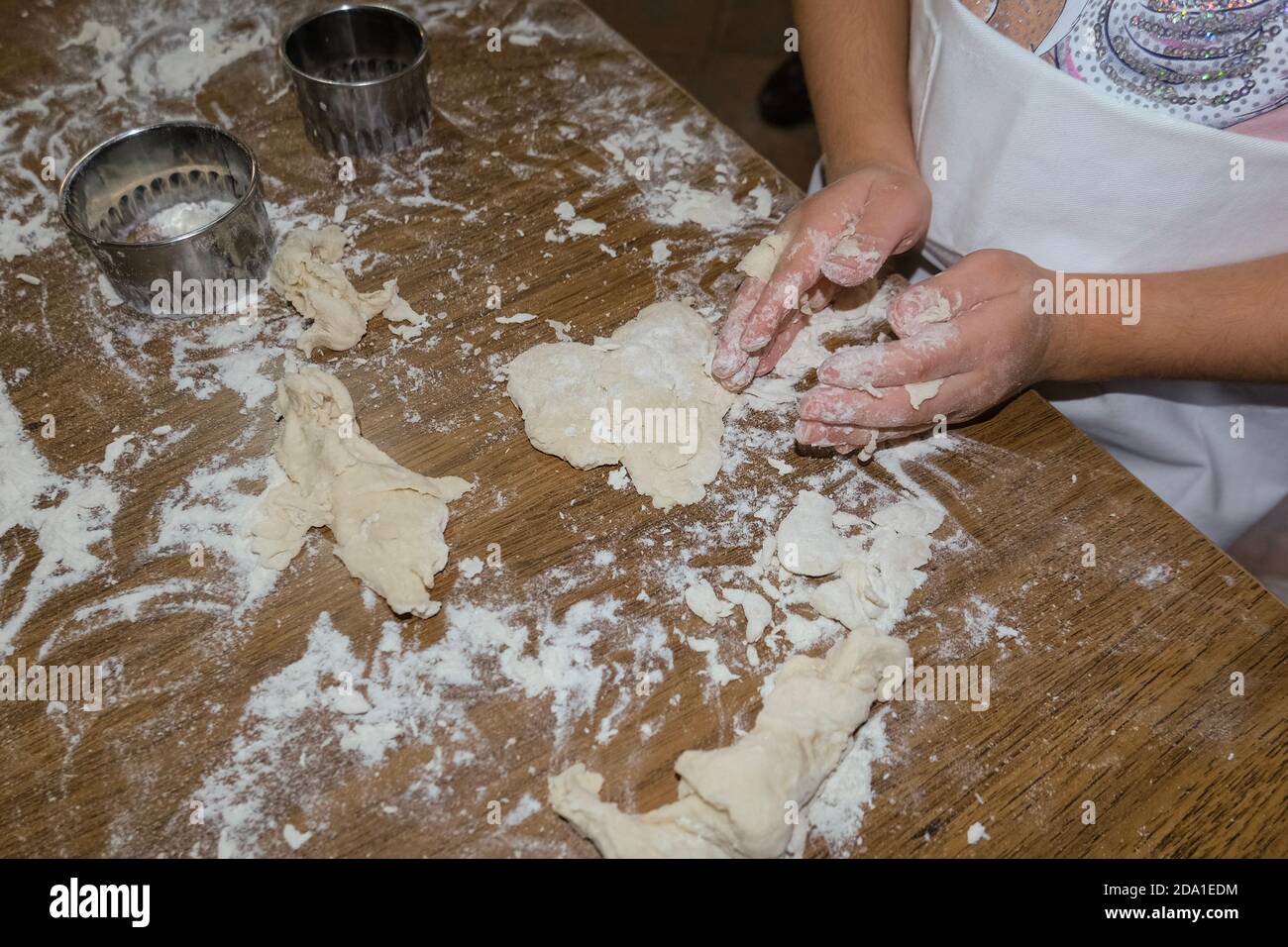 La bambina guarda le mani mentre gioca con pasta da pasticceria, figlia famiglia Foto Stock