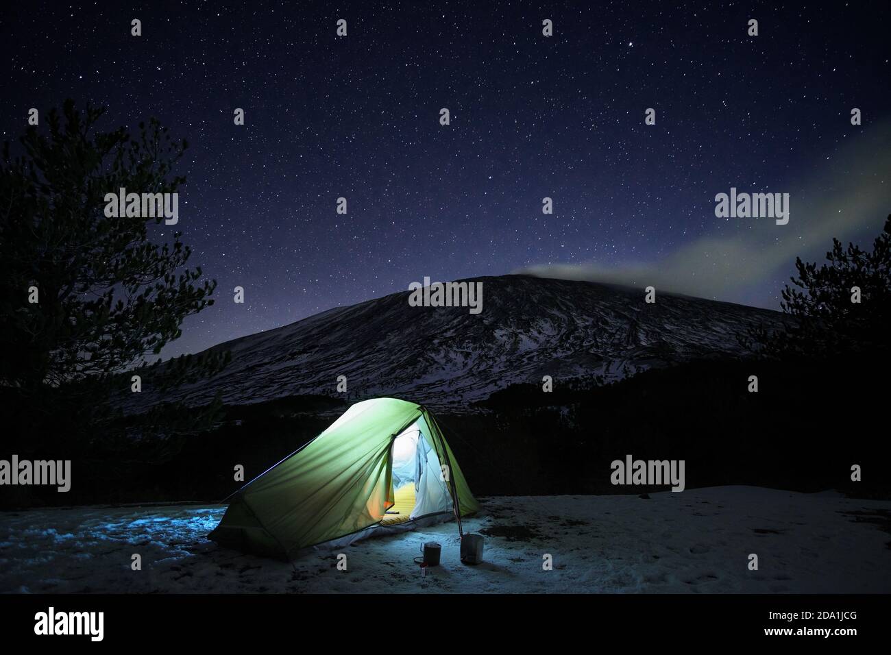 Cielo stellato su tenda verde illuminata nel paesaggio invernale del Parco dell'Etna, Sicilia Foto Stock