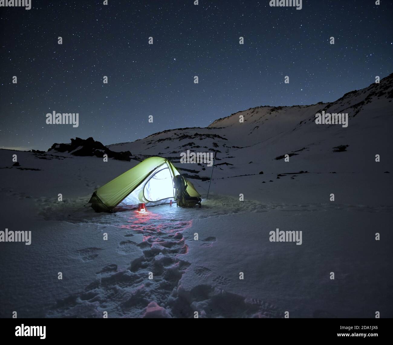 Tenda illuminata sulla neve ghiacciata sotto il cielo stellato nel Parco dell'Etna, Sicilia Foto Stock