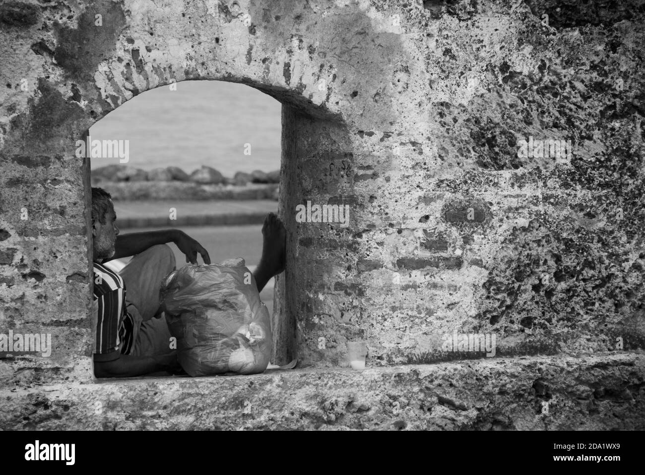 Un uomo senza casa cerca rifugio nei bastioni rovinati di Cartagena de Indias, Colombia Foto Stock