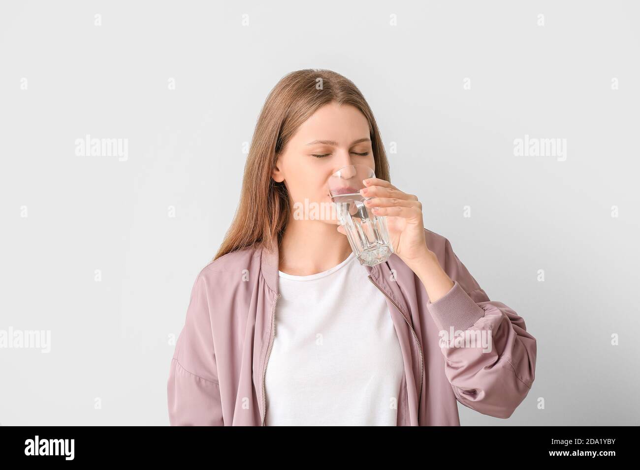 Donna con problemi di sete eccessiva su sfondo chiaro. Sintomi del diabete Foto Stock