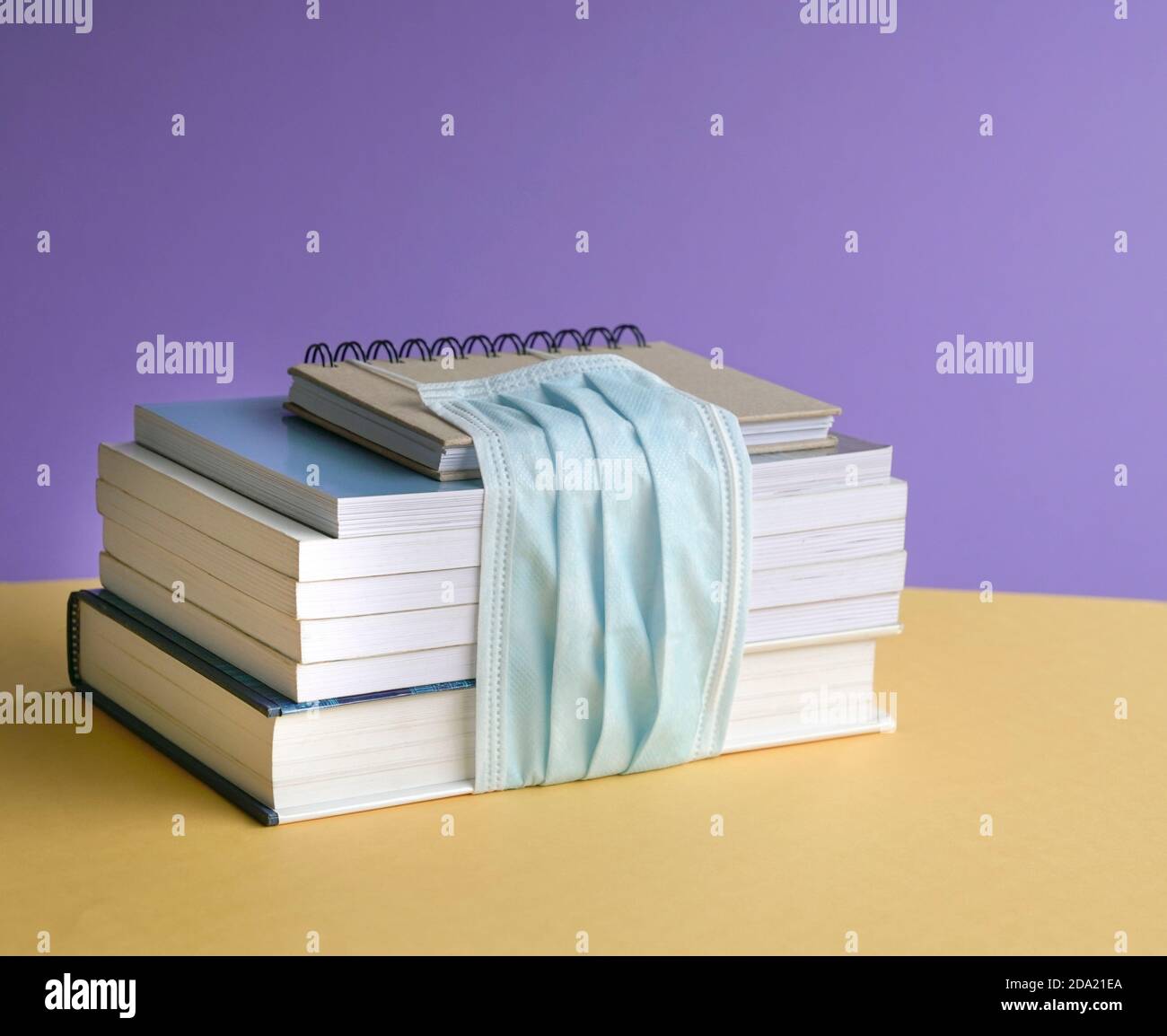 Libri impilati legati con maschera facciale. Ritorno a scuola durante il concetto di coronavirus. Foto Stock