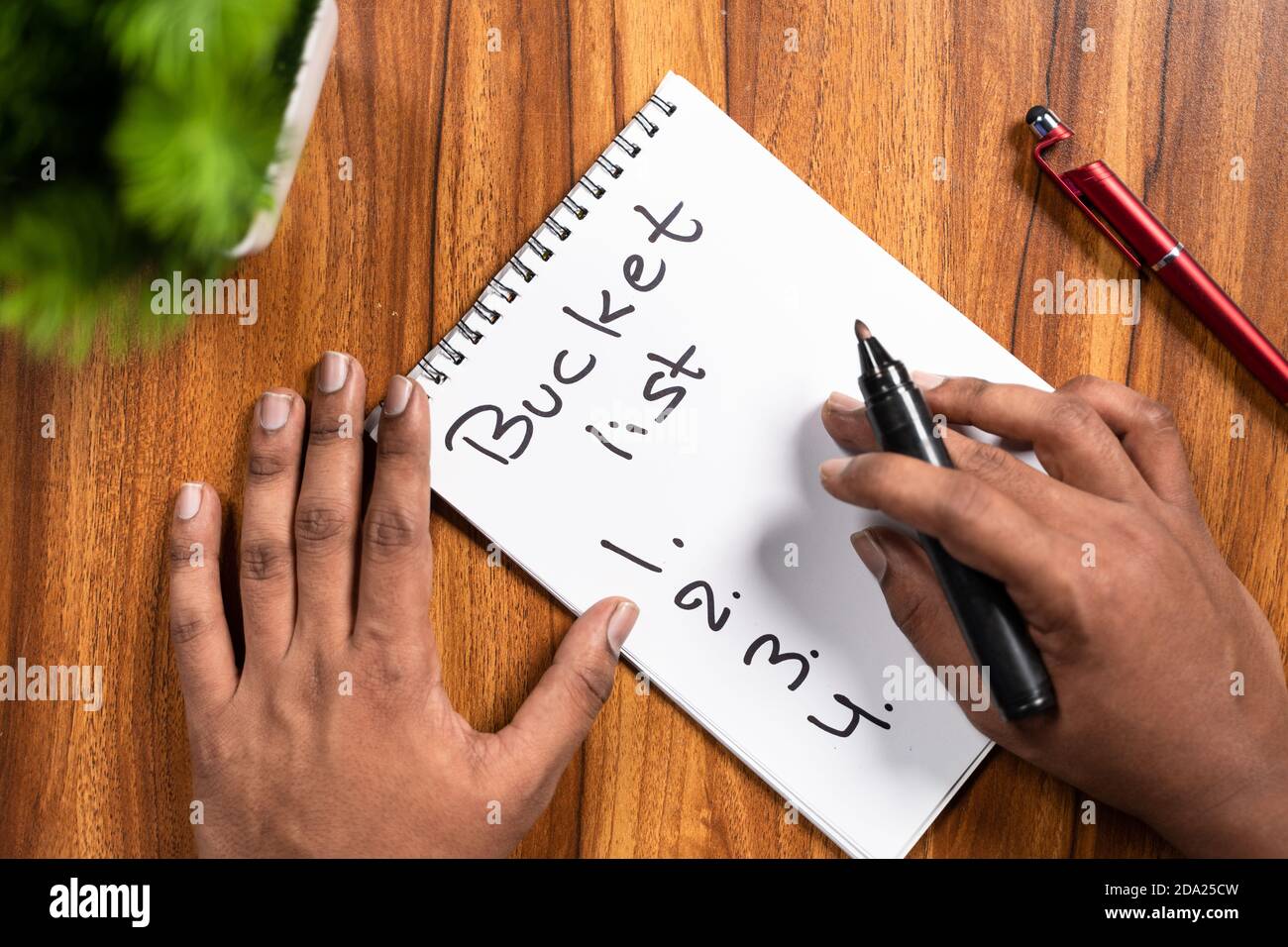 POV colpo di mani che scrivono o che pianificano giù l'elenco del bucket sul libro di note per il nuovo anno 2021. Foto Stock