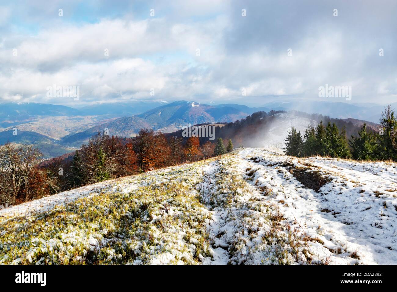 Bell'incontro d'autunno e d'inverno, un paesaggio con la neve del primo novembre tra le montagne con alberi di colore rosso Foto Stock