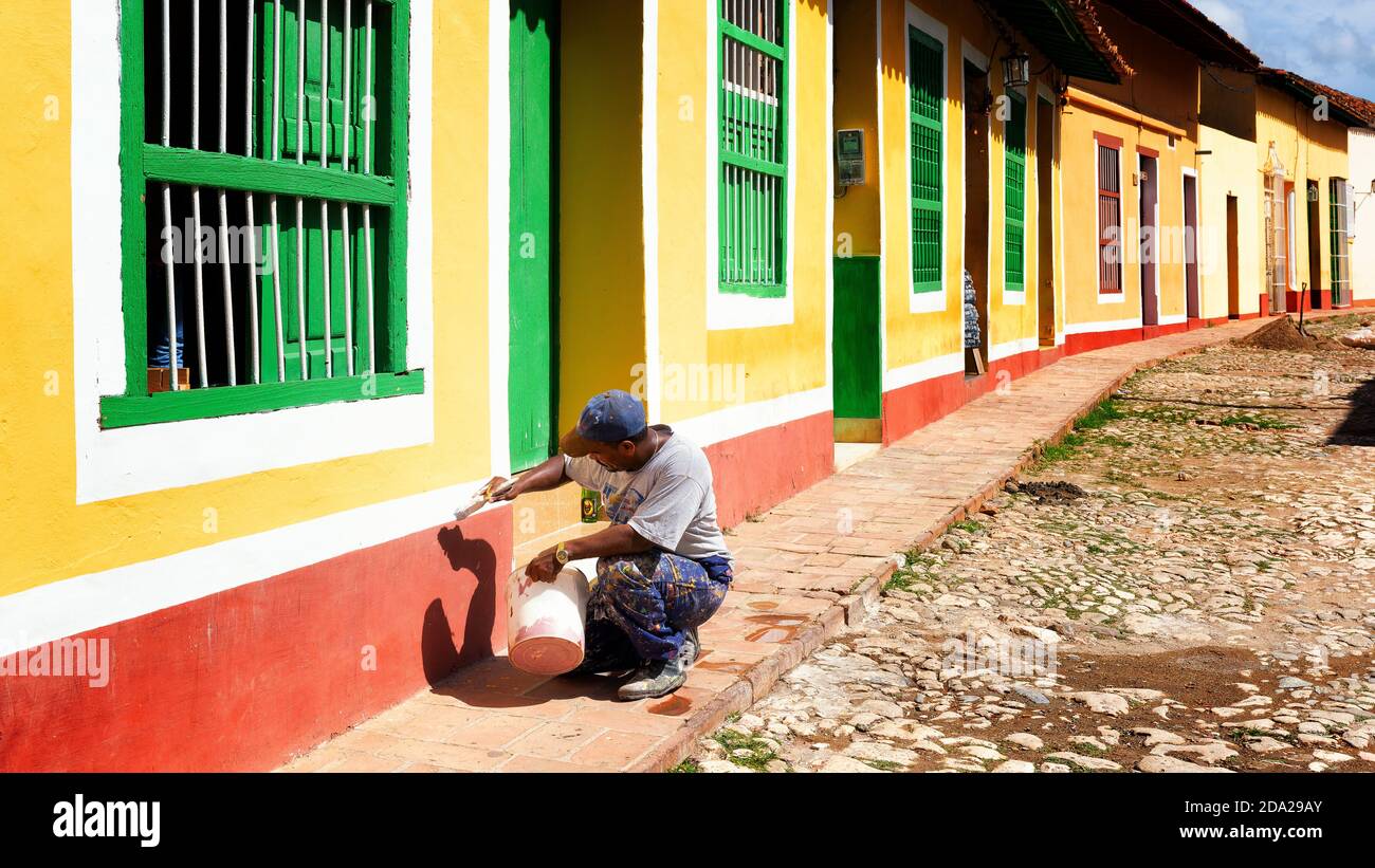 Uomo cubano che dipinge una facciata di casa. Trinidad case colorate. Foto Stock