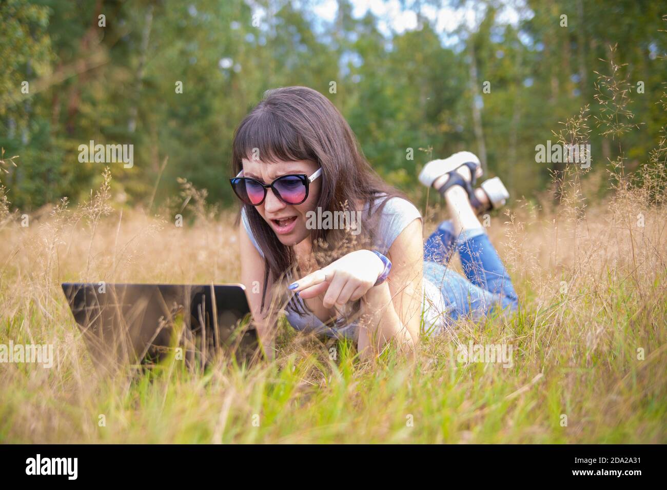 giovane donna che parla emotivamente al telefono davanti al computer portatile. Foto Stock