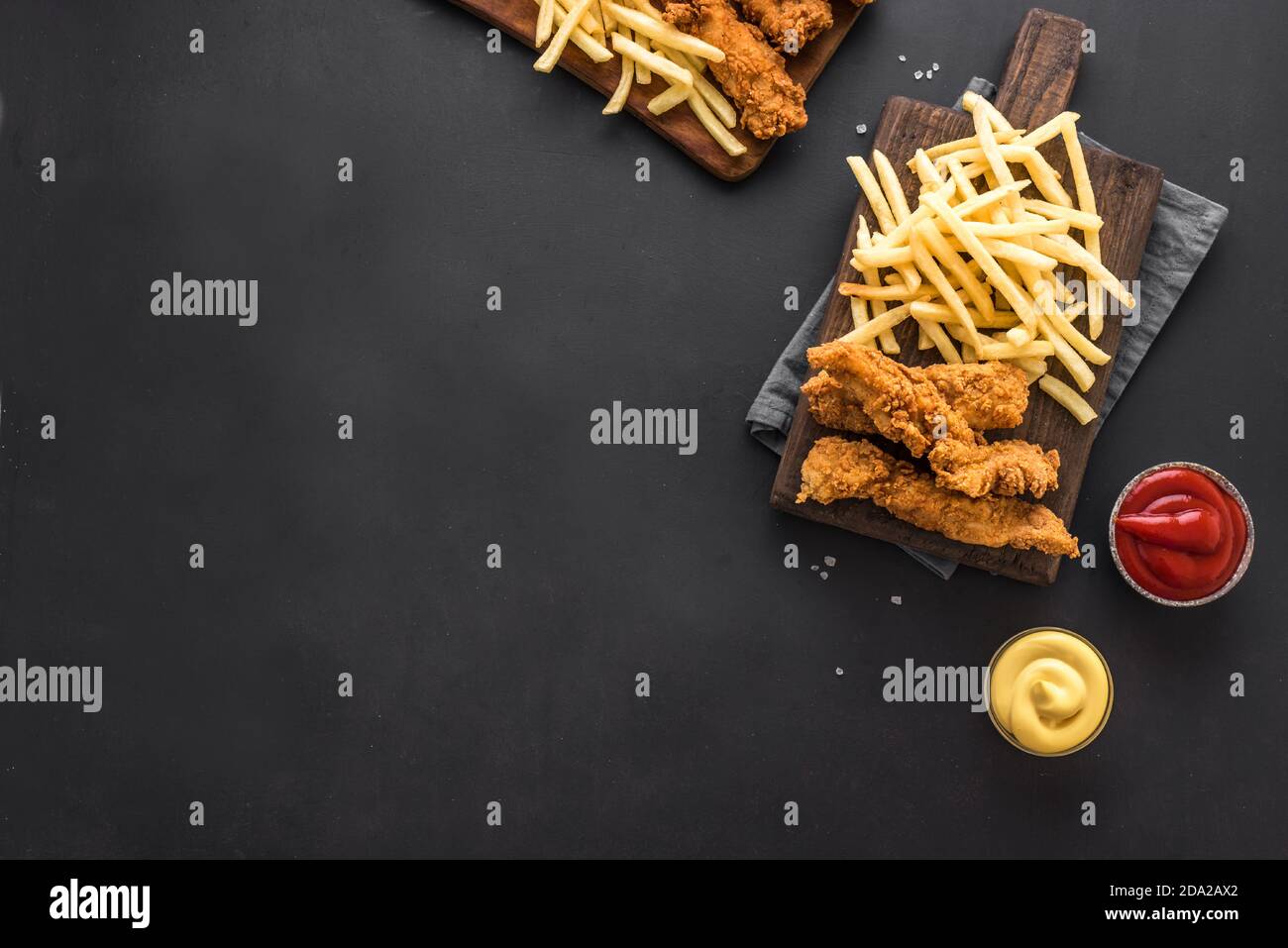 Pesce e patatine. Filetto di pesce fritto e con patatine fritte servite su tavola nera con salse. Cibo di strada tradizionale britannico, vista dall'alto, spazio fotocopie. Foto Stock