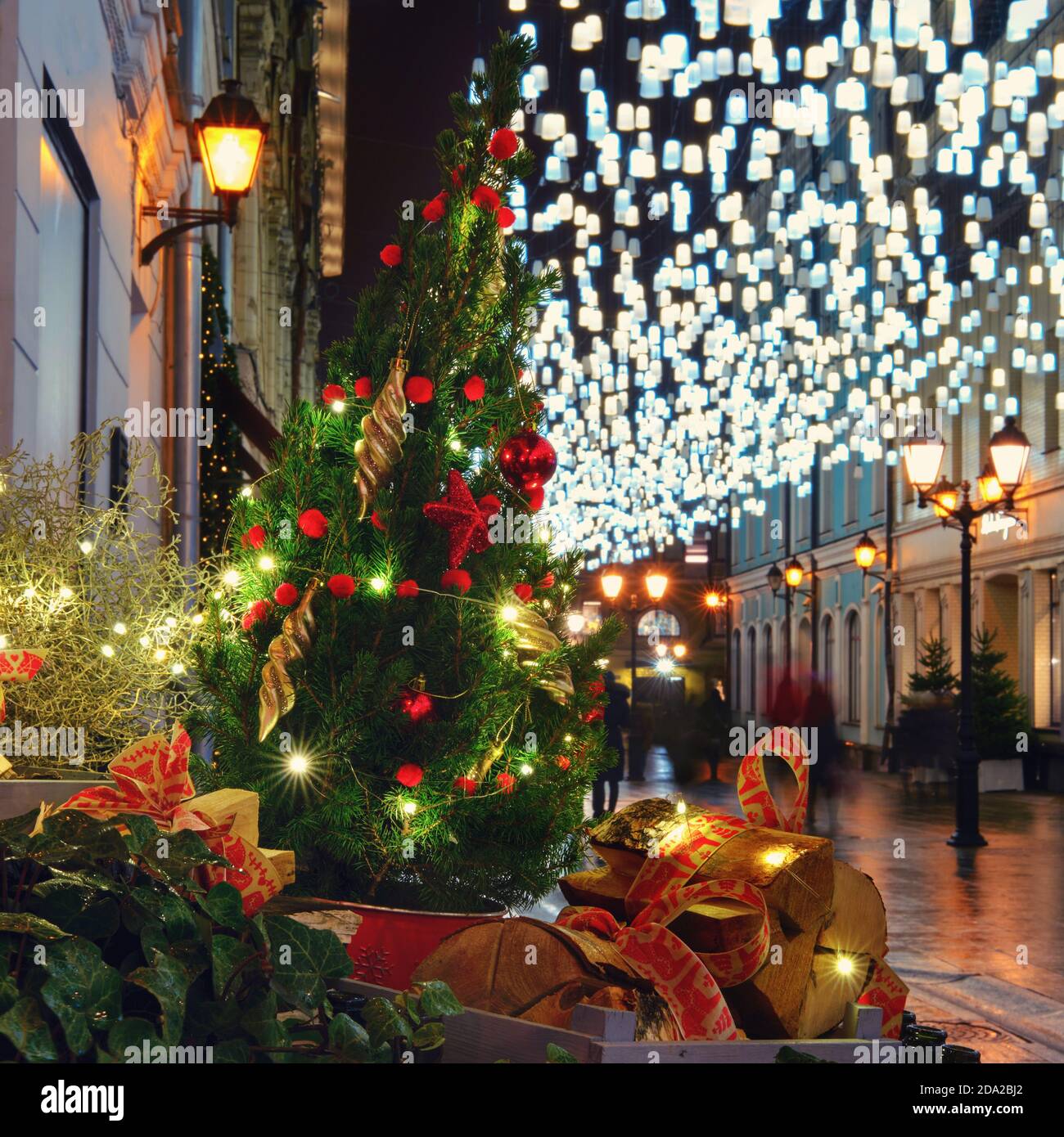 Decorazioni notturne sulle strade della città blu e lampada a luci dorate.  Albero di Natale con palle rosse la vigilia di Capodanno Foto stock - Alamy