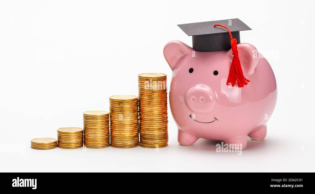 Banca di piggy in cappellino graduato vicino a pila di monete. Risparmi per l'istruzione. I prezzi dell'istruzione superiore. Isolato su sfondo bianco. Foto Stock
