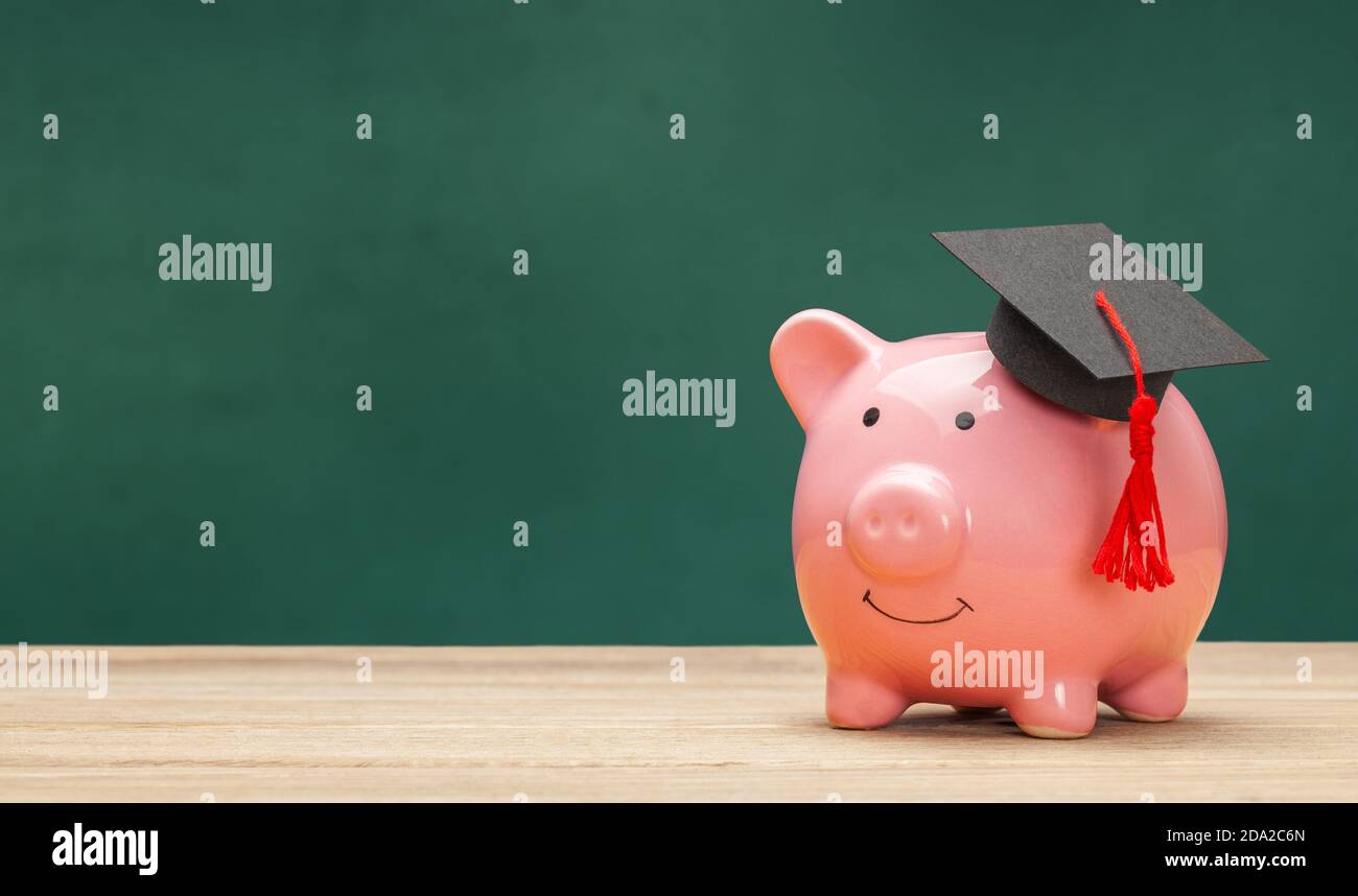 Piggy bank e nero laureato cappello isolato su sfondo bianco. Sfondo del consiglio di scuola verde Foto Stock