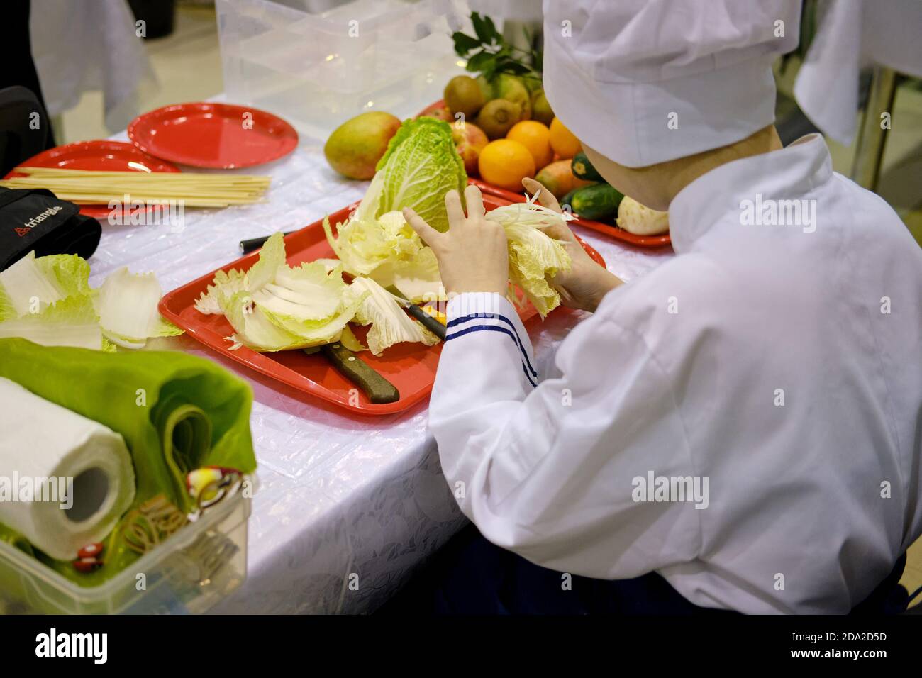 Un uomo carves modelli su cibo per decorare una tabella con verdure e frutta in forma di fiori Foto Stock