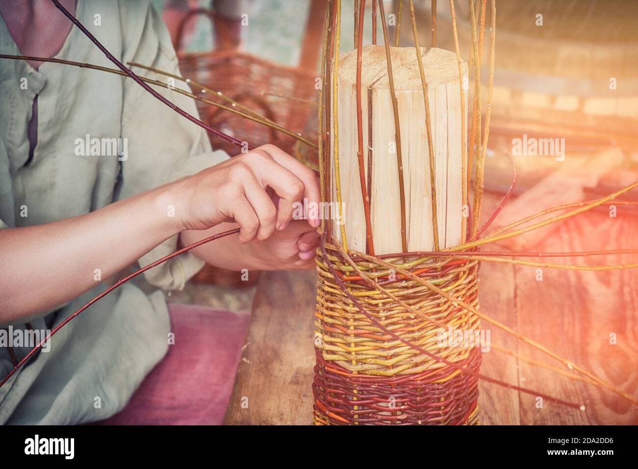 Un uomo tesse un cesto di rami di salice. Master Basketmaker crea al lavoro in Studio. Foto Stock