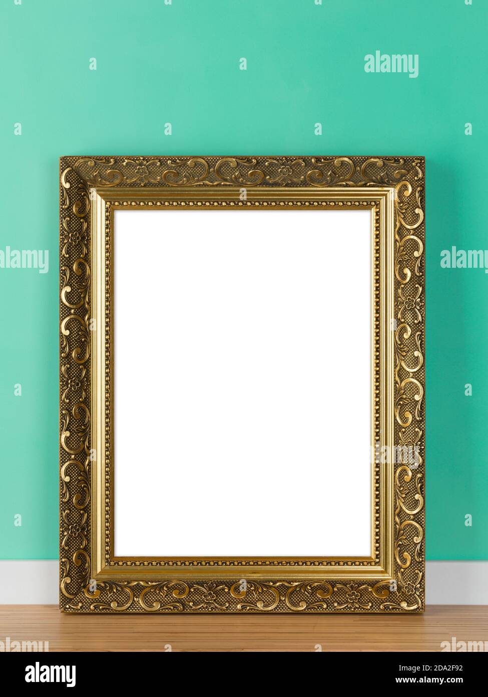 Cornice verticale dorata ornata appoggiata su una maschera mockup a parete verde. Area immagine vuota isolata con tracciato di ritaglio Foto Stock