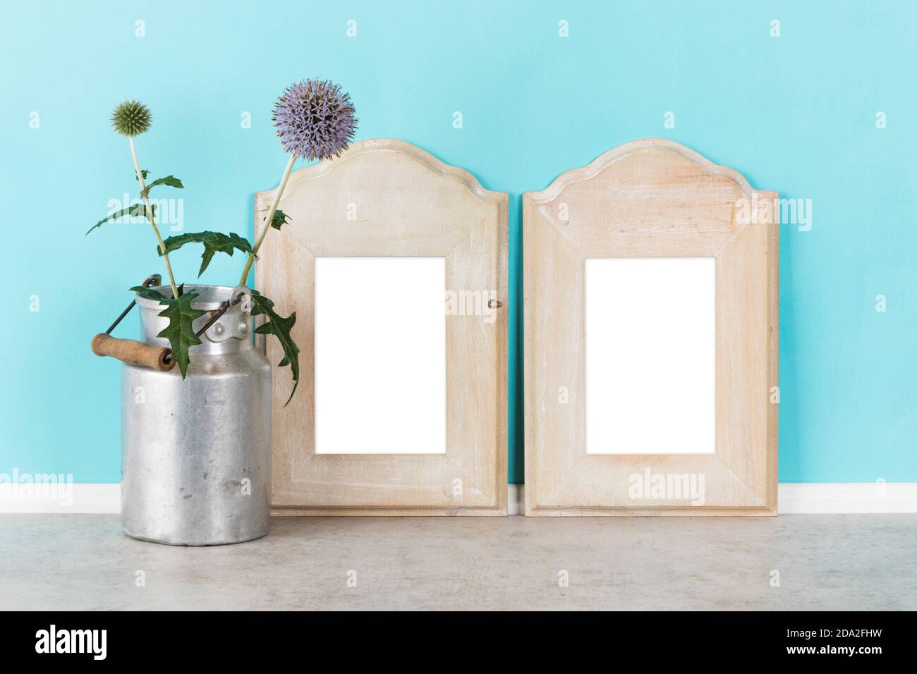 Rustico mockup modello sfondo con due shabby in legno chic verticale cornici da quadro e zanghetta di latte con fiori di cardo globo dentro fronte turchese Foto Stock