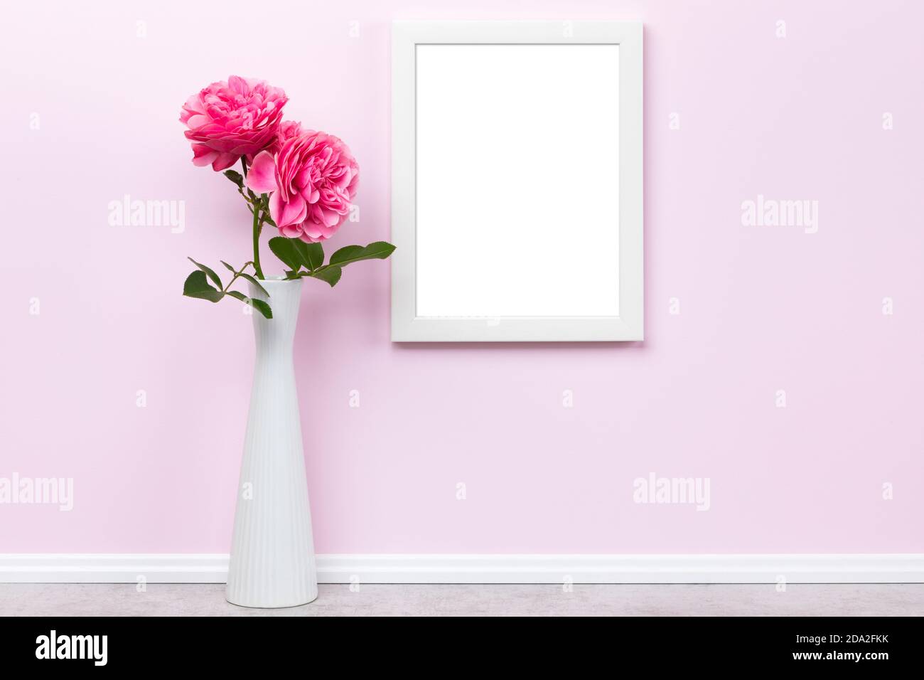 Cornice verticale bianca, formato 3x4, su parete rosa e rose in modello di vase mockup. Area vuota dell'immagine isolata con il tracciato di ritaglio Foto Stock