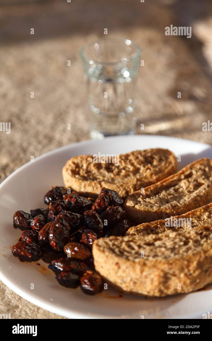 Cretese, olive e tsikoudia (raki), un delizioso pasto snack come spesso offerto a Creta. Tutti e tre i prodotti sono di tipica cucina cretese. Foto Stock