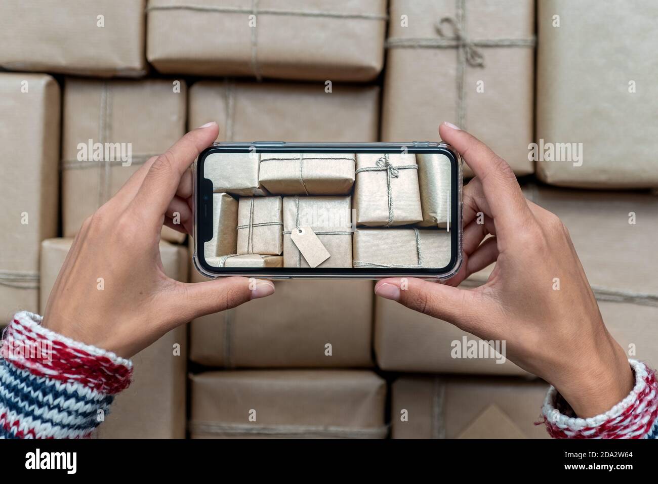 Donna che scattano una foto di regali di Natale impilati avvolti in carta artigianale Foto Stock