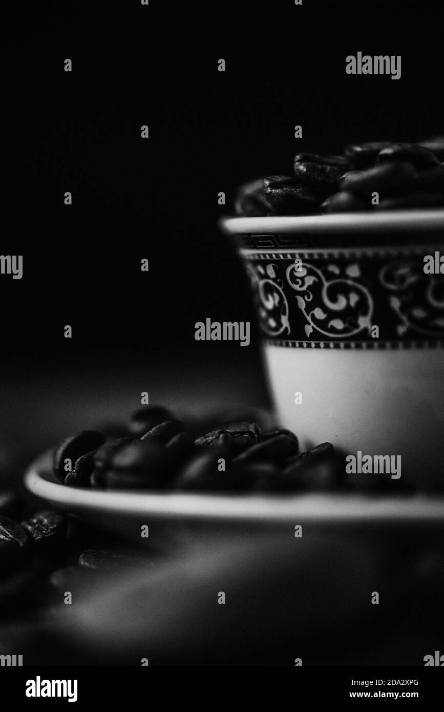 Colpo in scala di grigi di una tazza di caffè con chicchi tostati sfondo sfocato Foto Stock
