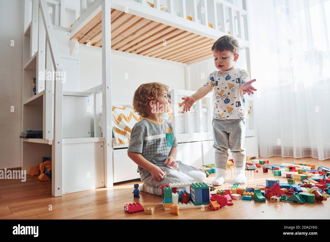 Due bambini piccoli si divertono all'interno della camera da letto con set per  costruzioni in plastica Foto stock - Alamy