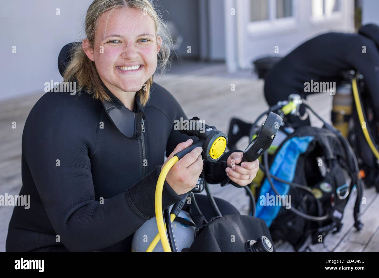 Subacquei che si kitting e controllare la loro attrezzatura, ragazza che guarda la macchina fotografica sorridente. Foto Stock