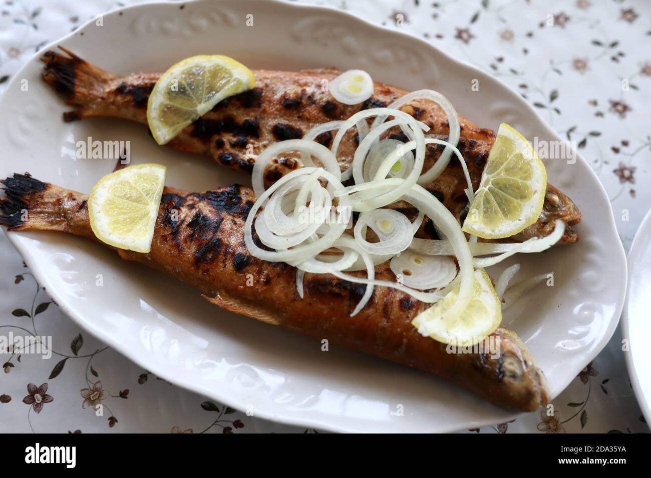 Trota alla griglia con cipolle sul piatto nel ristorante Foto Stock