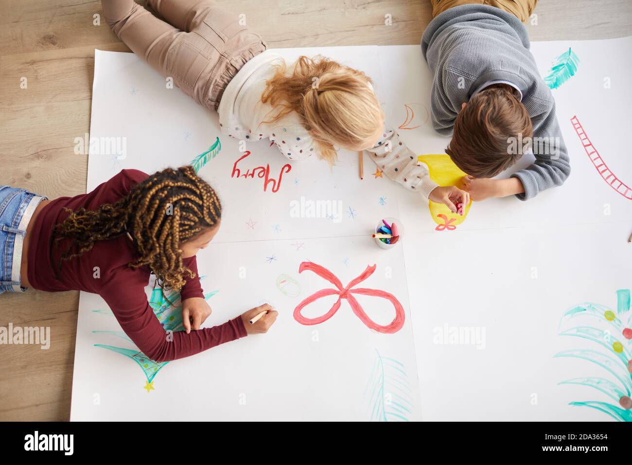 Vista dall'alto su un gruppo multietnico di bambini che disegnano immagini al piano mentre si godi la lezione d'arte a Natale, spazio copia Foto Stock