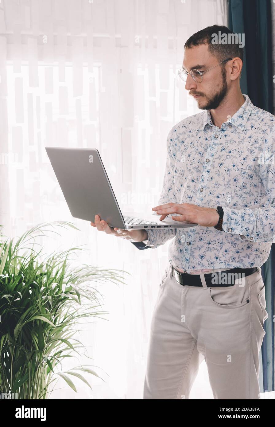 Giovane uomo che effettua una chiamata utilizzando il computer portatile per lavoro. Concetto di lavoro a casa durante 2020 covid coronavirus pandemia Foto Stock