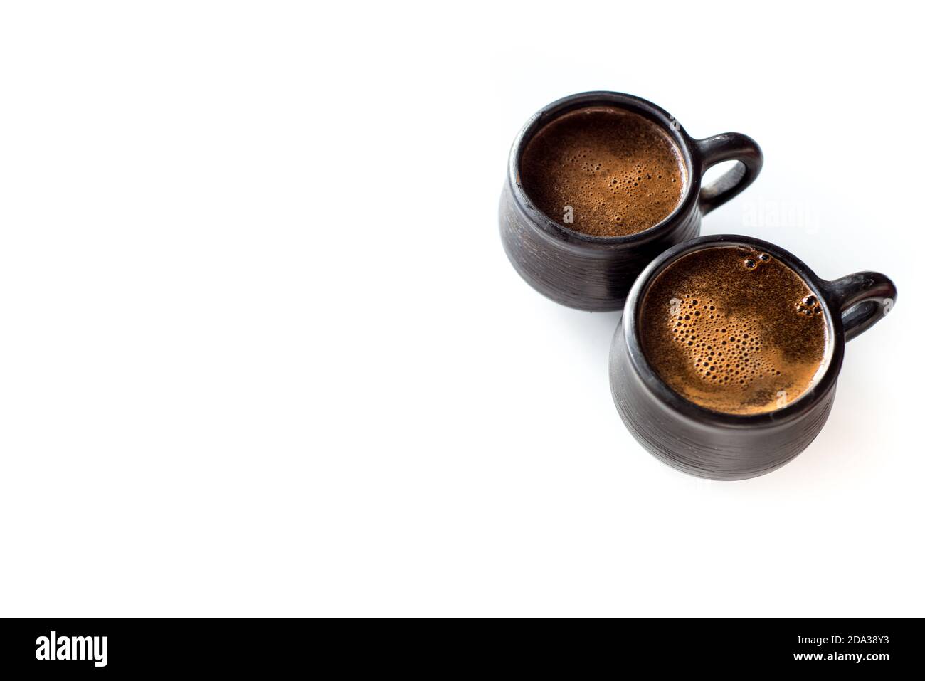 Due tazze da caffè in ceramica in terracotta nera isolate su un tavolo bianco. Caffè caldo aromatico del mattino Foto Stock