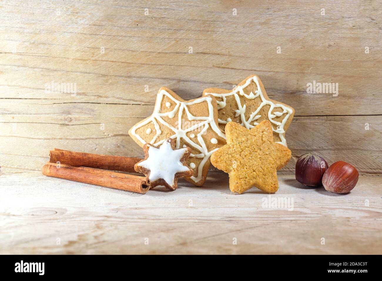 Biscotti di pan di zenzero a forma di stella, bastoncini di cannella e nocciole per Natale e Avvento, sfondo in legno rustico chiaro con spazio di copia, selezionato fo Foto Stock