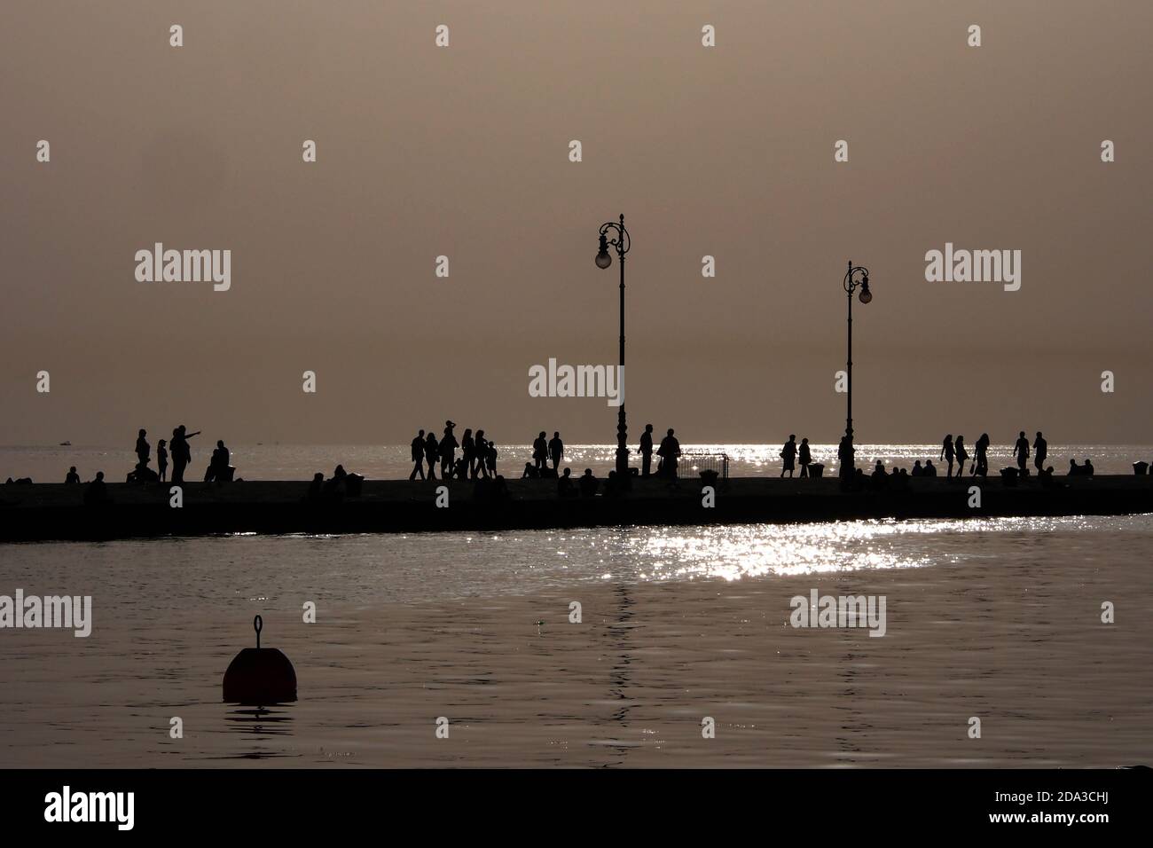 Trieste, Italia. Audace Molo. Persone che camminano alla luce della sera. Foto Stock